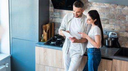 married couple using digital tablet together in kitchen, smart home concept